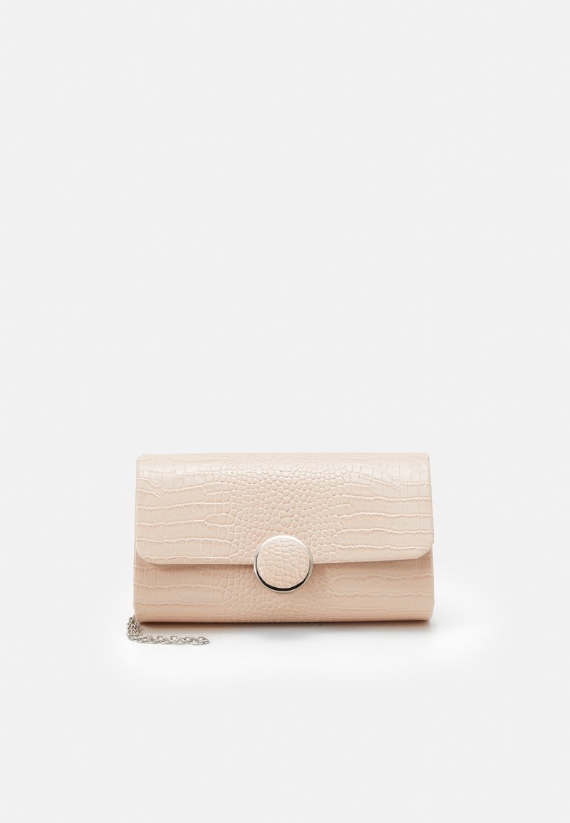 Pochette beige à motif crocodile avec fermoir rond argenté et une courte chaîne argentée sur fond blanc.