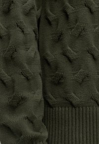 Tissu tricoté vert foncé avec motif torsadé en relief et ourlet côtelé au bord inférieur.