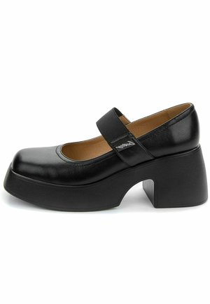 Chaussure Mary Jane en cuir noir avec semelle plateforme épaisse, talon bloc et bride élastique sur le cou-de-pied, doublure intérieure beige visible.