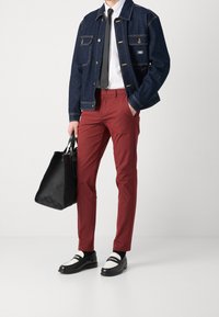 Kurtka dżinsowa z przednimi kieszeniami, biała koszula, czarny krawat, bordowe dopasowane spodnie, czarna torebka i czarne buty z białymi akcentami.