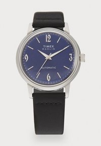 Ceas automatic Timex Marlin cu carcasă din oțel inoxidabil argintiu, cadran albastru, numere arabe albe și brățară din piele neagră.