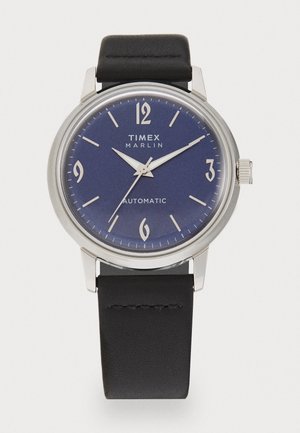 Timex Marlin automatic watch with a silver stainless steel case, blue dial, white Arabic numerals, and a black leather strap.