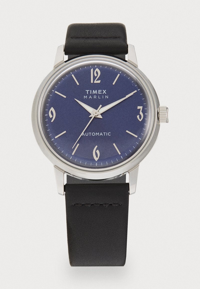 Timex Marlin automatinis laikrodis su sidabriniu nerūdijančio plieno korpusu, mėlynu ciferblatu, baltais arabų skaičiais ir juodu odiniu dirželiu.