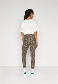 T-shirt blanc à manches courtes associé à un legging imprimé léopard. Les leggings ont une coupe ajustée avec une texture lisse et une taille haute.