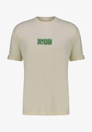Beżowy t-shirt z krótkim rękawem wykonany z bawełny, z zielonym logo "DRYKORN" w stylizowanym stylu, umieszczonym na środku klatki piersiowej.