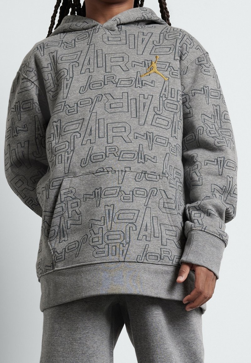 Graue Kapuzenjacke mit einem durchgehenden grafischen Muster, das die Worte "AIR" und "JORDAN" zeigt. Enthält eine Kängurutasche und eine Ziehkordel an der Kapuze.