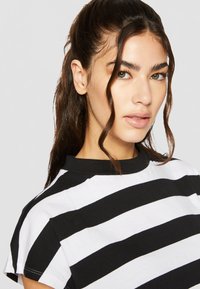 Zwart-wit gestreept t-shirt met een ronde halslijn en korte mouwen. De stof lijkt glad met een casual, ontspannen pasvorm.