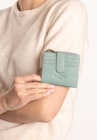 Compact mintgroene leren portemonnee met een gestructureerde afwerking, voorzien van drie kaartsleuven en een ritsvak voor muntgeld.