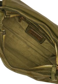 Interno di una borsa in pelle verde oliva con foderatura in tessuto a righe beige. Presenta una tasca con zip e un'etichetta del marchio cucita.