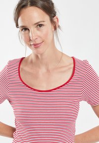 T-shirt rayé rouge et blanc à manches courtes, col rond et coupe ajustée. Tissu doux avec une texture lisse.