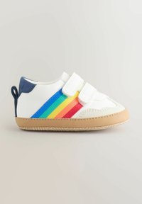 Weiße Sneaker mit einem Regenbogenstreifen an der Seite, ausgestattet mit zwei Klettverschlüssen und einer hellbraunen Gummisohle. Navyblaue Fersendetails sind ebenfalls enthalten.