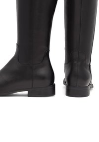 Stivali neri in pelle al ginocchio con una finitura liscia, tacco basso a blocco e dettagli di cucitura sottili lungo i lati e il retro.