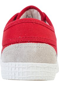 Baskets en toile rouge avec un talon en suède beige texturé et une semelle en caoutchouc blanc à motif tissé. Design minimaliste, style à enfiler.