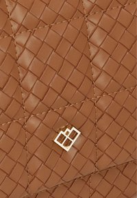 Brun flettet lædertaske med diamantformet quiltet mønster. Har guld logo hardware i midten. Glat tekstur og detaljeret syning.