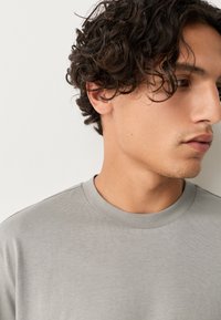 Gray crew-neck t-shirt made of smooth cotton fabric, featuring short sleeves and a simple, minimalist design without patterns or accents.