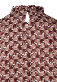 Brown and white patterned fabric featuring geometric shapes with alternating warm and cool tones. Ruffled neckline with a keyhole detail.