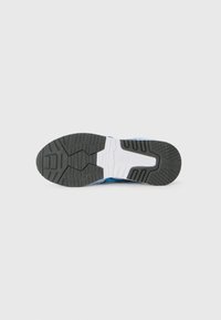 Sola de um sapato atlético azul com borracha preta texturizada, entressola branca e padrão de material antiderrapante para melhor aderência. Apresenta o logótipo da ASICS.
