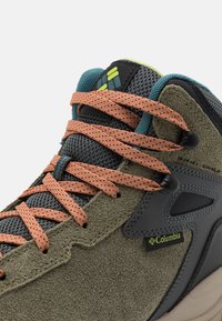 Szare sznurowane buty trekkingowe z zamszu i siateczki, z pomarańczowymi sznurówkami, czarnymi akcentami i zielonymi metkami z logo. Posiadają wyściełany kołnierz i teksturowaną podeszwę.