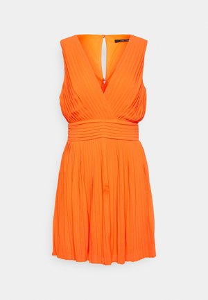 Ärmelloses, helloranges, plissiertes Kleid mit tiefem V-Ausschnitt und figurbetonter Taille, auf hellem, einfachem Hintergrund präsentiert.