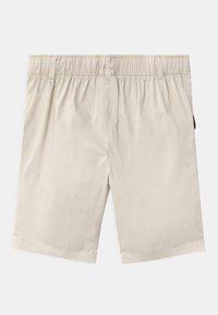Béžové kraťasy s elastickým pasem, hladkým povrchem a bočními kapsami. Design se vyznačuje čistými liniemi a minimálním zdobením.