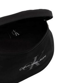 Zwarte ritstas gemaakt van duurzaam materiaal. Bevat logo tekst "Calvin Klein Jeans" in het wit en heeft een gladde, onvergrate bediening.