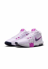 Hvide og lyserøde Nike sportssko har et struktureret overdel, mesh-paneler, en fremtrædende swoosh, og en polstret sål med en synlig Air-enhed.