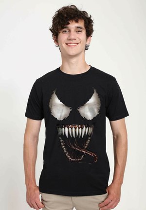 Black cotton t-shirt featuring a graphic of a menacing face with white eyes and sharp teeth, designed with intricate details and textures.