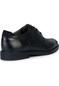 Scarpe da uomo in pelle nera con finitura liscia, punta arrotondata, design con lacci e suola in gomma nera testurizzata con scanalature orizzontali.