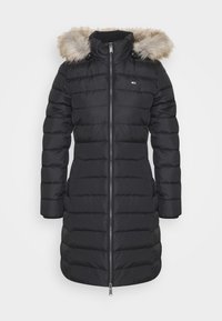 Giacca imbottita nera con cappuccio in pelliccia sintetica, motivo a righe verticali, chiusura con zip frontale e tasche laterali. Design sartoriale per il calore.