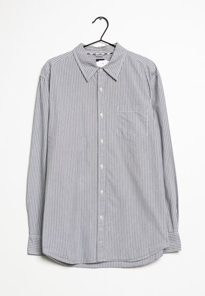 Szaro-biała koszula z długim rękawem w paski, z kołnierzykiem i kieszonką na piersi. Tkanina wydaje się gładka i ma miękką fakturę.