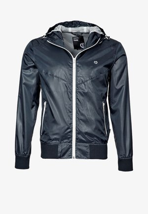 Tmavě modrá lehká bunda s kapucí, bílým zipem a zipovanými kapsami, žebrovanými manžetami a lemem a nenápadným logem na hrudi.