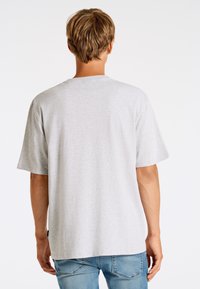 Grå bomullströja med korta ärmar, rund hals och avslappnad passform. Anmärkningsvärda egenskaper inkluderar en mjuk textur och en etikett på den nedre sidan.