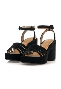 Sandalias de plataforma de ante negro con múltiples tiras cruzadas, hebilla en el tobillo y un tacón grueso. Plantilla suave con un diseño texturizado.