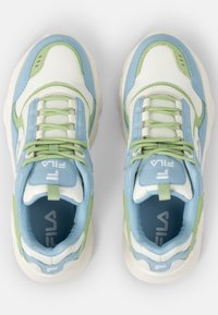 Sneakers har en ovandel i mesh med vita, ljusblå och gröna accenter. Rundad form, texturerat material och platta snören. Fila-logotyp på tungan.