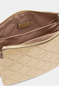 Borsa in pelle beige con texture e zipper dorato. Interno foderato in tessuto rosa, dotato di etichetta del marchio e due scomparti per la conservazione.