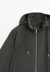 Dark green hooded jacket with front zipper and drawstrings, showing upper front and brand label inside collar.