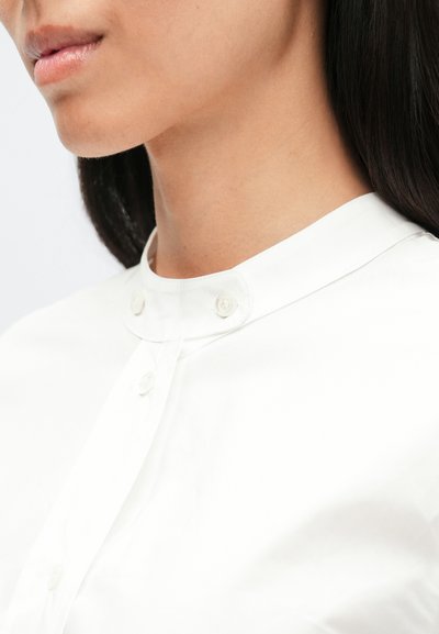 Λευκό βαμβακερό πουκάμισο με στρογγυλεμένο γιακά με δύο κουμπιά, απαλής υφής και καθαρό, δομημένο σχέδιο.