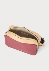 Piccola borsa con una parte inferiore color marrone scuro, una parte superiore beige chiaro e accessori in oro. Presenta una chiusura con zip e pelle texturizzata.