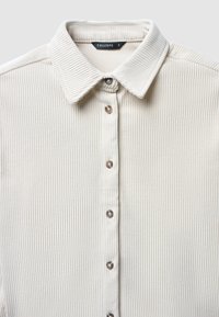 Camicia in corduroy crema con colletto, chiusura frontale con bottoni e trama a coste sottile, dotata di bottoni simili a perle.