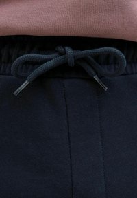 Marineblå træningsbukser med tekstureret finish og elastisk talje, der har en vævet snoretræk foran til justering.