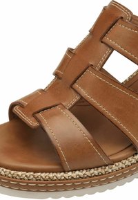Sandalo in pelle marrone con un design intrecciato, fasce spesse e una suola in stile espadrille texturizzata. Nota il contrasto con le cuciture bianche.