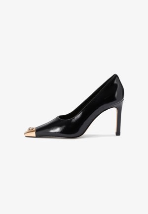 Escarpin noir en cuir verni à talons hauts avec un bout pointu, un capot doré métallique et un détail décoratif sur le bout. Design à talon aiguille.