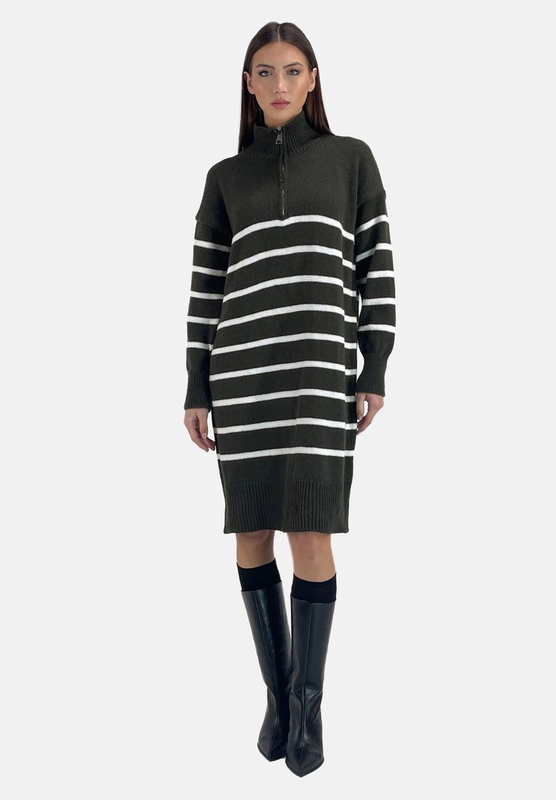 Vestito a maglione verde scuro con strisce orizzontali bianche, colletto alto e polsini a coste, abbinato a stivali neri a punta al ginocchio.