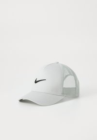 Szara siatkowa czapka z solidnym szarym przednim panelem i czarnym logo Nike. Posiada zakrzywiony daszek oraz oddychające siatkowe boki.