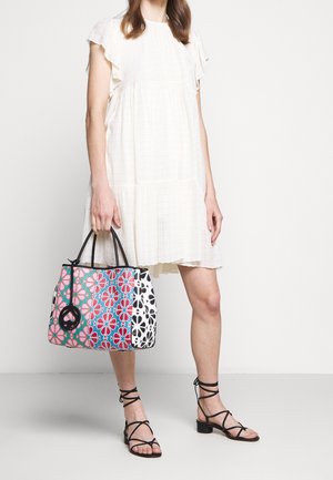 Borsa a mano multicolore con motivi floreali, caratterizzata da dettagli neri e una combinazione di sezioni rosa acceso, blu e bianche. Manici robusti.