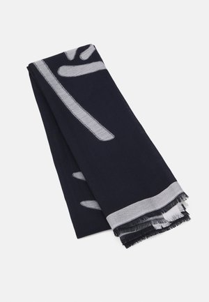 Écharpe bleu marine avec motifs abstraits gris clair et bords frangés, soigneusement pliée sur un fond blanc.