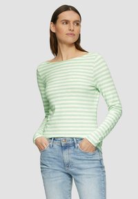 Haut à manches longues rayé vert clair avec un col bateau, en tissu doux. Assorti à un jean bleu clair, présentant un style décontracté.