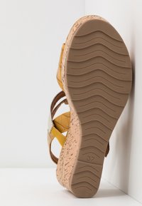 Sandale compensée avec semelle en liège, brides en cuir jaune à motif matelassé, et un accent contrastant gris clair. Taille indiquée 37.