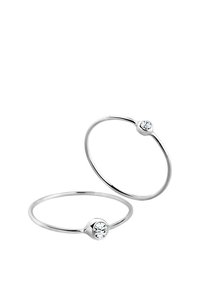 Dos anillos minimalistas de plata con una sola gema transparente engastada en una banda delgada, creando un diseño elegante y moderno.