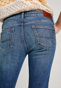 Mörkblå denimjeans med slim fit, som har två bakfickor, subtila sömdetaljer och en läderlapp vid bakre midjan.